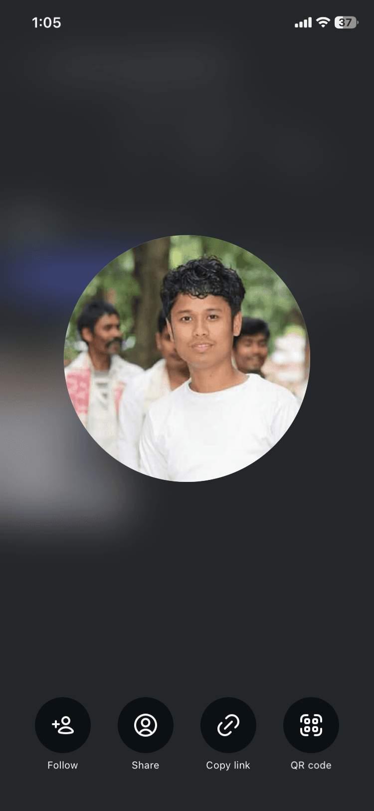 सफेद टी-शर्ट पहने और मुस्कुराते हुए घुंघराले बालों वाले एक युवक की गोलाकार प्रोफाइल तस्वीर।