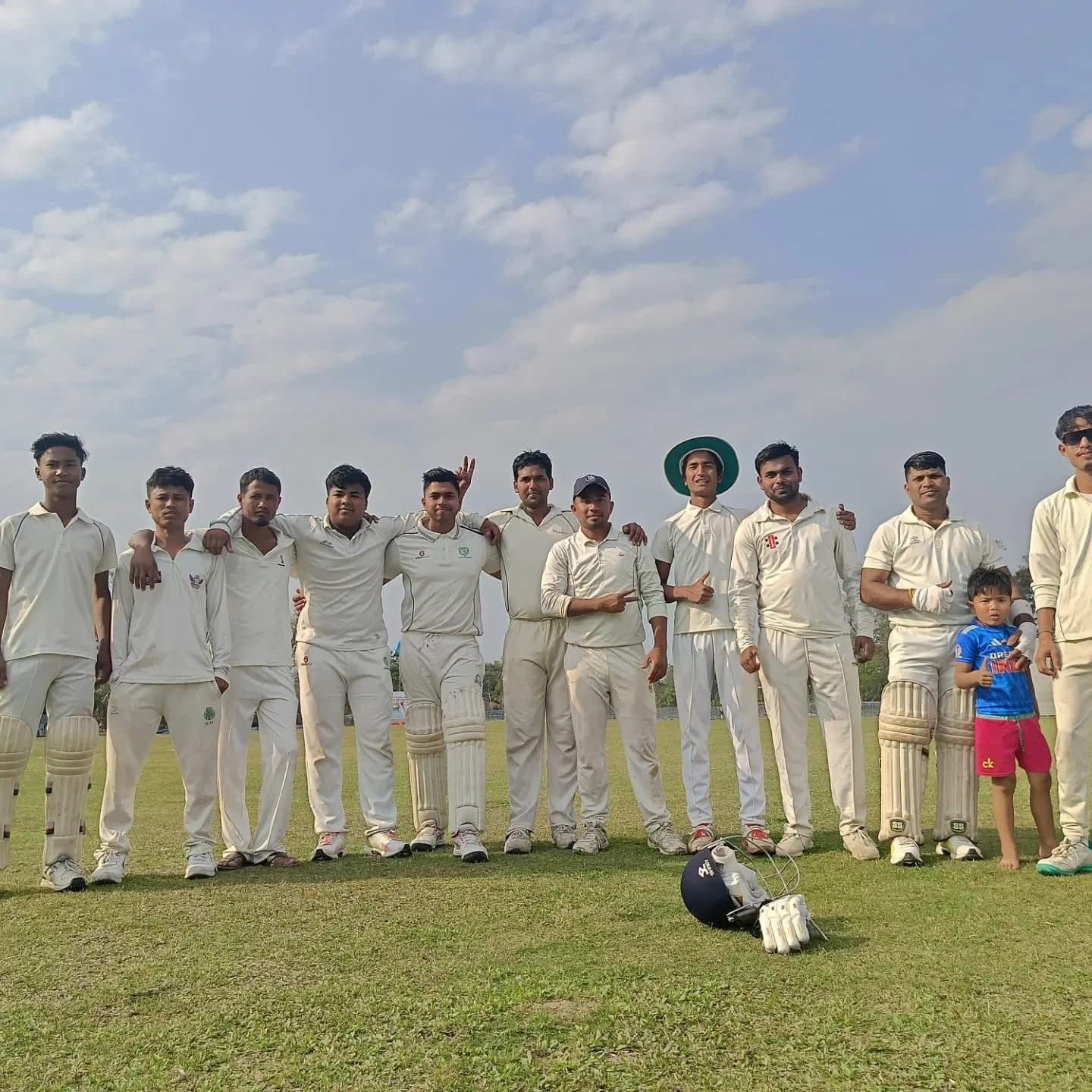 सफेद वर्दी पहने क्रिकेट खिलाड़ियों का समूह खुले मैदान में एक साथ खड़ा है।